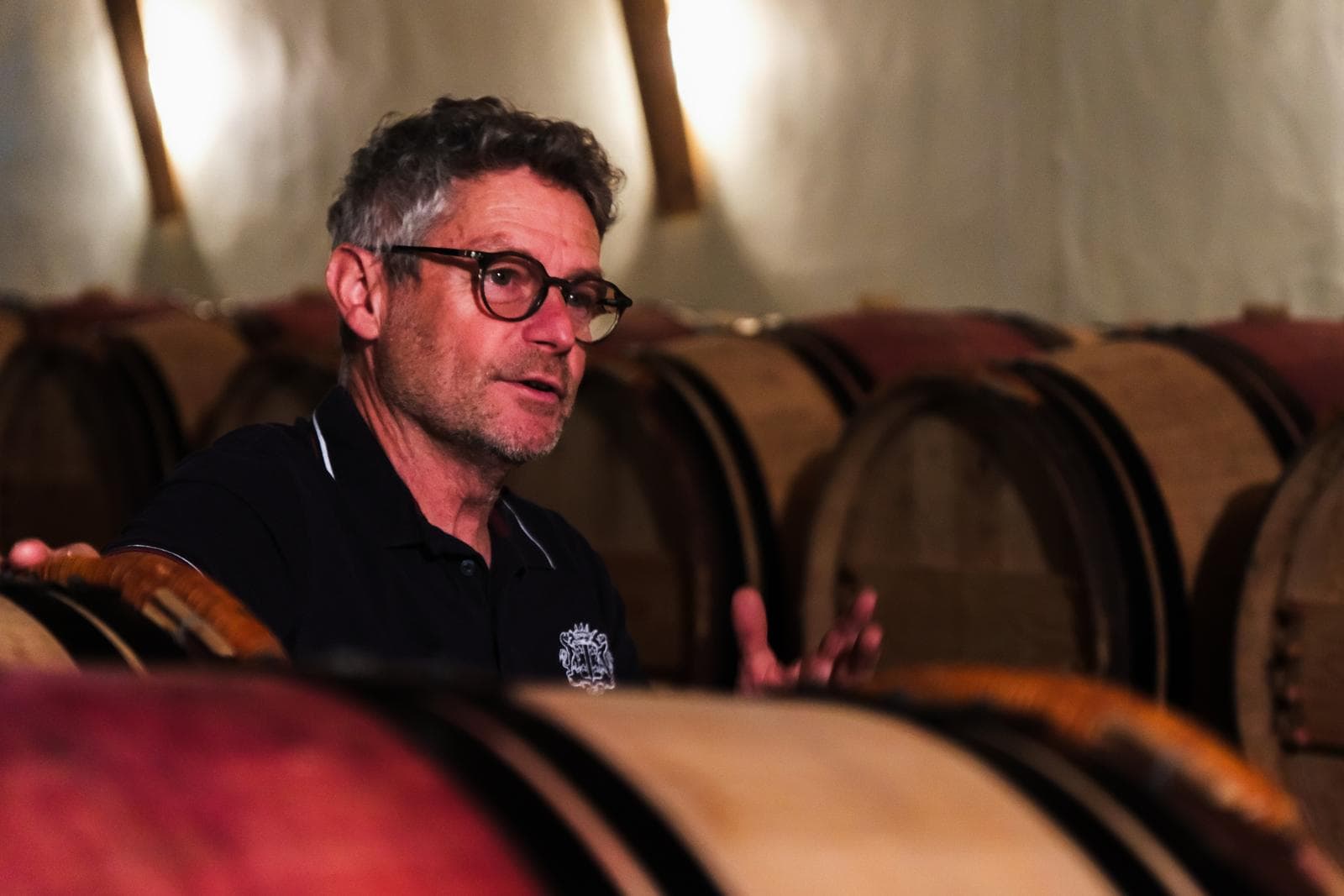 Vigneron expliquant son élevage, accoudé à une barrique