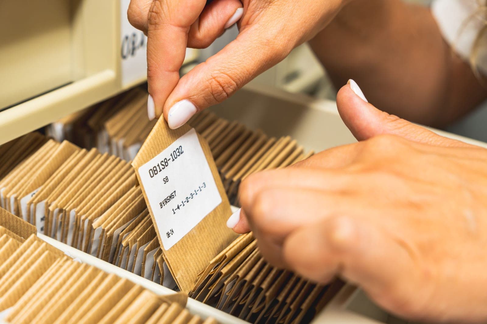 Mains qui sortent une fiche d’archive étiquetée d’un tiroir de la collection génétique